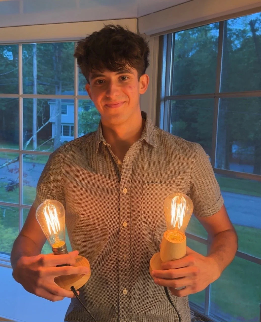 Diego, founder of Strainless Lighting, holding two warm incandescent bulbs